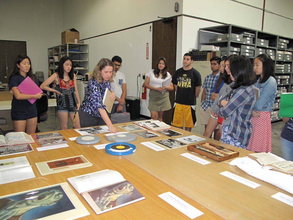 Sandra Yates, archivist, shows collection materials to Rice University students at the McGovern Historical Center, pointing to the 1969 film, Staged Cardiac Replacement from the Texas Heart Institute Film Collection (IC043). Along with some of the photos on the table, the film documents the first artificial heart transplant by Dr. Denton Cooley and Dr. Domingo Liotta.