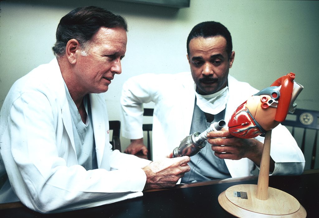 Photograph of Dr. Denton Cooley and Dr. John C. Norman with a model of a heart at the Texas Heart Institute, 1976.