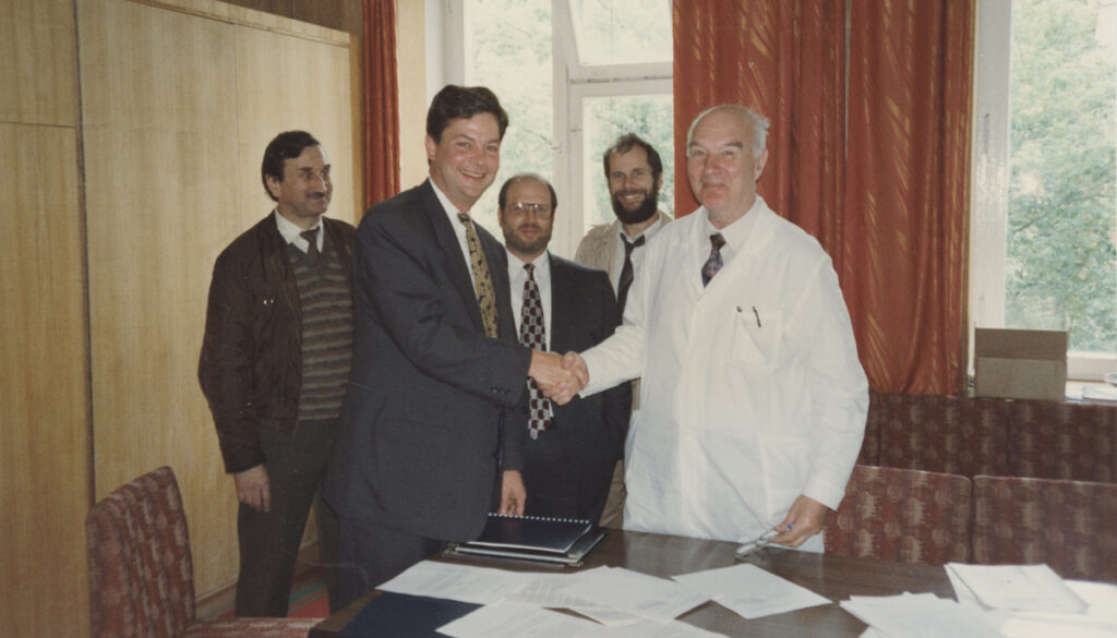 [Phillip Robinson shaking hands with the Russian Health Minister at a signing cermony, July 1993. Armin Weinberg and their guide Nikita stand in the background. MS 233 Phillip D. Robinson, MHA, LFACHE papers, box 1, folder 8, McGovern Historical Center, Texas Medical Center Library]