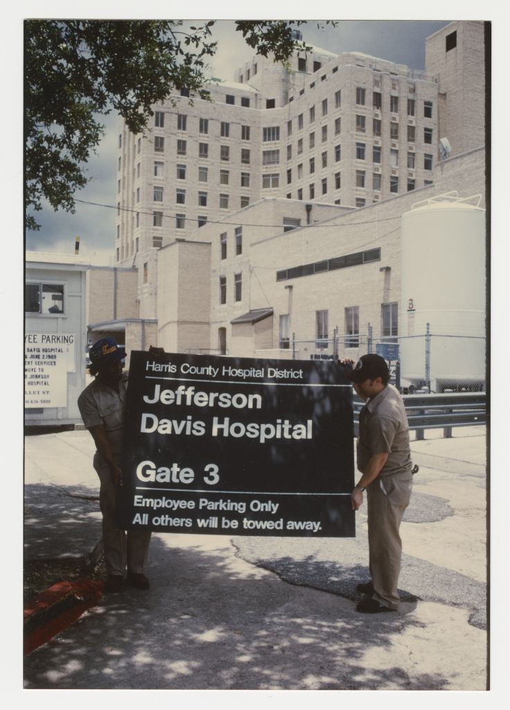 [Maintenance workers holding sign for Jefferson Davis Hospital in front of hospital, 1989. MS054-b4f1-006, Murdina MacFarquhar Desmond, MD papers, McGovern Historical Center, Texas Medical Center Library] 